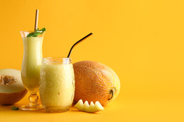 Glasses of tasty melon smoothie with mint on orange background