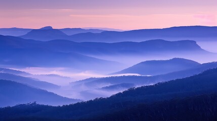 Fototapeta premium Mountain Ridges Shrouded in Mist During Soft Sunrise