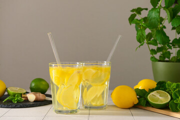 Glasses of tasty lemonade with mint and lime on white tile table