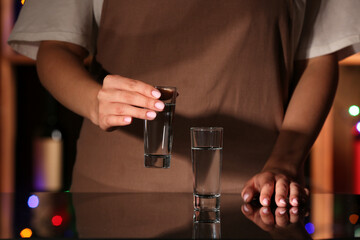 Woman with shots of cold vodka at table in bar
