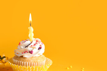 Delicious birthday cupcake with burning candle on yellow background