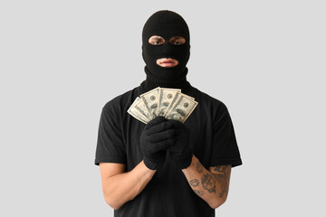 Male thief with dollar banknotes on grey background
