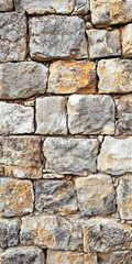 Fototapeta premium Close-up of weathered stone wall with rough textures and natural colors