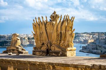 Traditional Maltese Architecture Malta Buildings Traditional Houses and Streets Tourism Concept Travel Background Exotic Mediterranean. Cityscape of Valletta in the background of a crown statue.