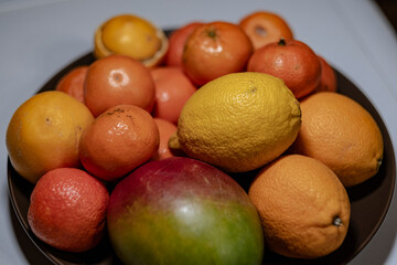 Plate with oranges, lemons, tengerines and mango fruit