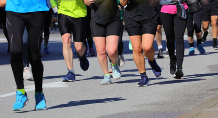 Obraz premium legs of people running including overweight women with large thighs to lose weight