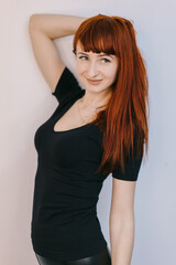 Model in casual outfit. A confident model with long red hair strikes a playful pose while wearing a black shirt and smiling.