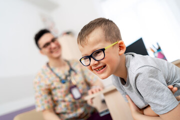 Smiling child during a doctor's visit. A happy child with glasses is laughing while playing at a...