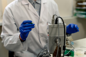 Tech conducts lab tests. A laboratory technician in a coat and gloves performs testing with a...