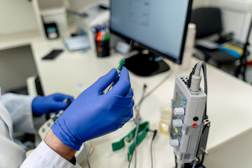 Med pro readies test sample. A lab technician in gloves holds a syringe while preparing a sample at...