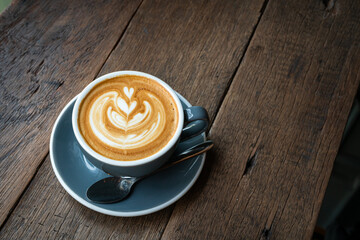 Hot coffee latte with latte art milk foam in cup mug on wood desk on top view. As breakfast In a coffee shop at the cafe,during business work concept,vintage style