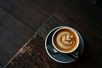 Hot coffee latte with latte art milk foam in cup mug on wood desk on top view. As breakfast In a coffee shop at the cafe,during business work concept,vintage style