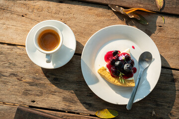 Hot coffee espresso in cup mug and Homemade Blueberry cheesecake wood desk on wood desk on top view. As breakfast In a coffee shop at the cafe,during business work concept