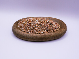 Wooden bowl of wheat, on green background, side view, close-up