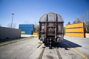 Goods depot, railway wagon for the transport of goods stopped on the tracks between containers