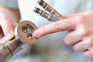 A close-up of a mixer with flexible hoses for cold and hot water installed. Preparing to replace...