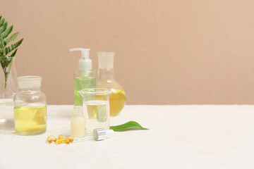 Laboratory glassware with ingredients and samples for preparing natural cosmetics on white table near beige wall