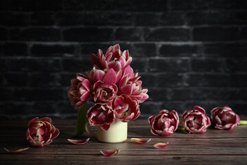 composition with pink terry tulips located in a white mug on a wooden table