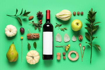 Bottle of wine with fruits and autumn decor on green background