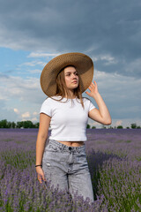A woman in a straw hat stands in a field of purple flowers