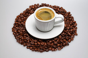 Coffee cup and saucer on roasted coffee beans. Isolated on a white background.