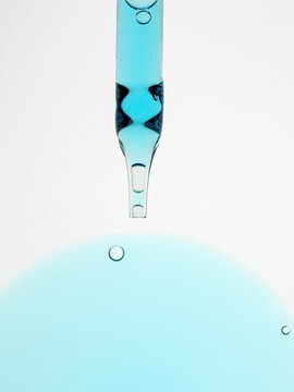 Cosmetic pipette above blue liquid with bubbles in motion
