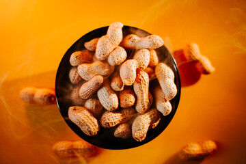 Peanuts in a black bowl surrounded by a warm golden background