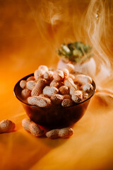 Warm bowl of roasted peanuts with steam rising, set against a golden background creating a cozy atmosphere