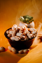 Steaming bowl of roasted peanuts with a succulent plant on a warm background