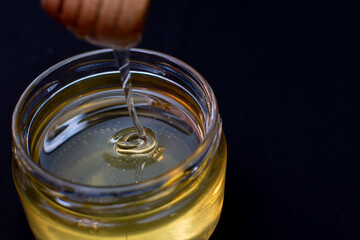 A person is carefully pouring honey into a glass bowl for use