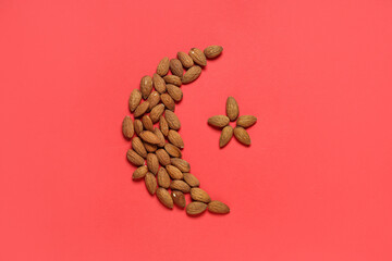 Crescent and star made of almond nuts on red background. Ramadan celebration