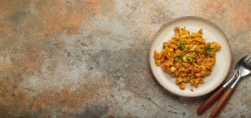 Plate of delicious and flavorful akuri, a traditional indian dish of scrambled eggs cooked with onions, tomatoes, spices, and herbs top view with copy space