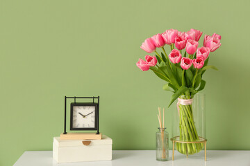 Bouquet of beautiful tulip flowers and clock on dresser near green wall