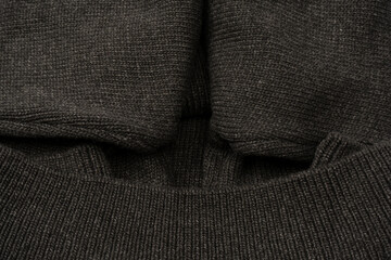 Dark grey sweater texture as a background. Knitted pattern.