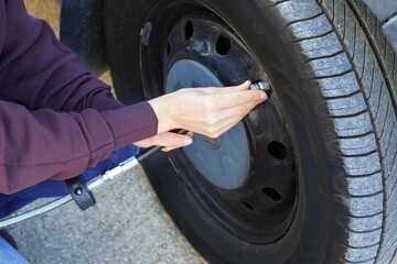 woman's hands checking the air pressure of her camper van's tires before the trip