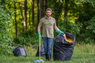 Volunteer collecting garbage, ecology. Man in rubber gloves with trash bag clean garbage. Man...