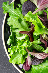 Fresh salad leaves mix salad juicy healthy snack micro greens, arugula, lettuce, oak leaf, green leaf salad tasty food background on the table rustic food top view copy space vegetarian and vegan