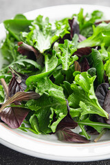 Fresh salad leaves mix salad juicy healthy snack micro greens, arugula, lettuce, oak leaf, green leaf salad tasty food background on the table rustic food top view copy space vegetarian and vegan
