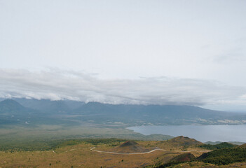 Panoramic view from Osorno Volcano, showcasing the city and lake below. A breathtaking contrast between the towering peak, the serene waters, and the urban landscape in the distance