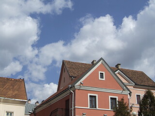 Close-up of historic European buildings with red-tiled roofs and pastel-colored facades under a partly cloudy sky