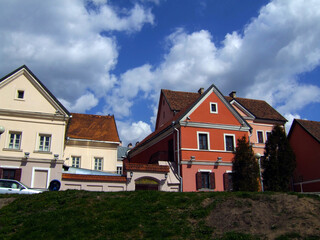 Traditional European houses with red-tiled roofs and colorful facades against a bright blue sky with white clouds in a historic district