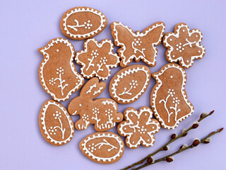 Romantic decorated Easter gingerbread cookies of various shapes with willow twigs, violet background