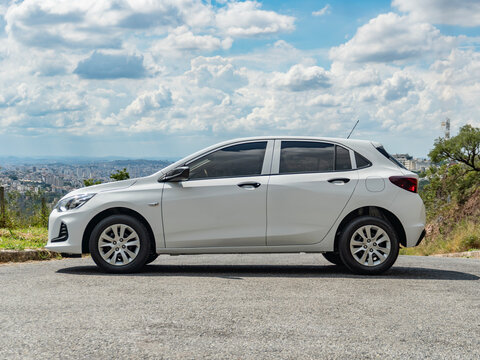 White Chevrolet Onix side view, Hatchback car with sky and clouds background, High resolution