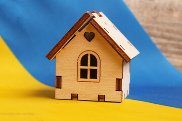 wooden house on the background of the flag of Ukraine. Concept of military operations in Ukraine