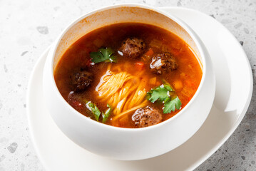 A bowl of flavorful meatball soup with noodles, garnished with fresh herbs. The dish features a rich broth and appetizing meatballs, perfect for comfort food lovers.