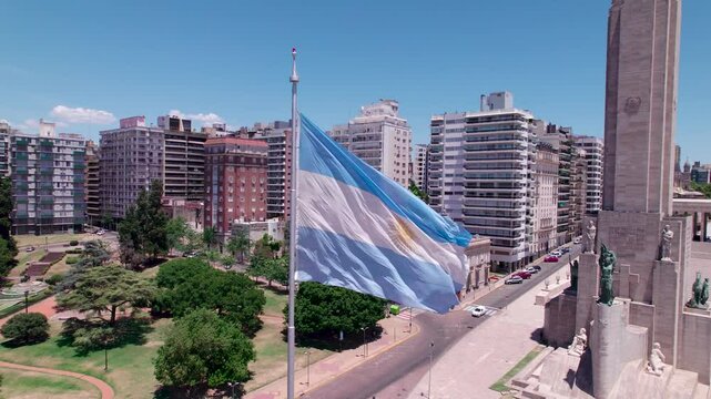 Vista a&eacute;rea de la bandera argentina flameando frente al Monumento Hist&oacute;rico Nacional a la Bandera, Monumento a la Bandera. Rosario, Santa Fe, Argentina. D&iacute;a soleado, Belgrano, turismo, patria
