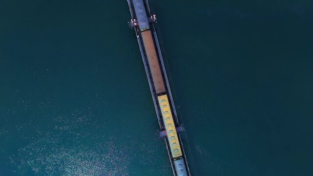 Top view drone shot showing a train passing over the historic World War II bridge over the River Kwai. It is now maintained and usable as a historical tourist attraction in Kanchanaburi, Thailand.