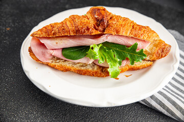 Sandwich croissant ham, cheese, green leaf salad delicious gourmet food background on the table rustic food top view copy space