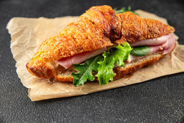 Sandwich croissant ham, cheese, green leaf salad delicious gourmet food background on the table rustic food top view copy space