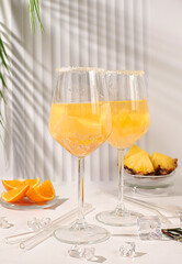 Summer party concept. Tequila, rum and vodka cocktail with pineapple, orange, ice and rosemary slices. Diet drink for body detox and weight loss, advertising for a bar or cafe, menu for a restaurant.